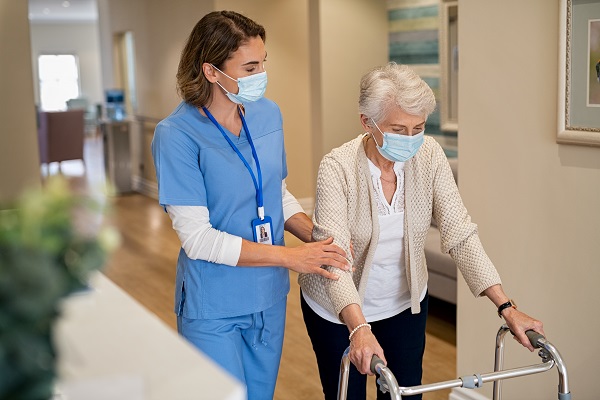 Nurse helping senior woman walk at nursing home.
