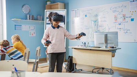 Young female student wearing augmented reality headset and using controllers learns lessons in virtual reality