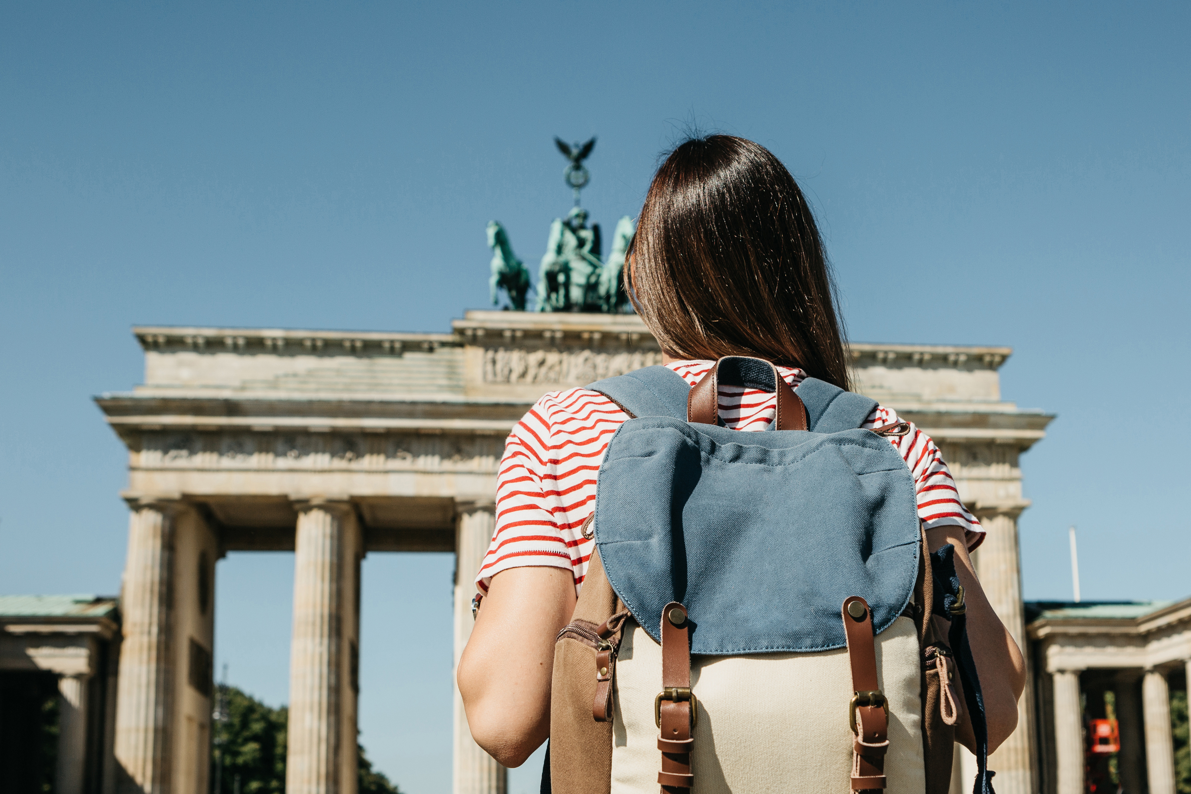 A tourist or a student with a backpack near the Brandenburg Gate in Berlin in Germany, looks at the sights.